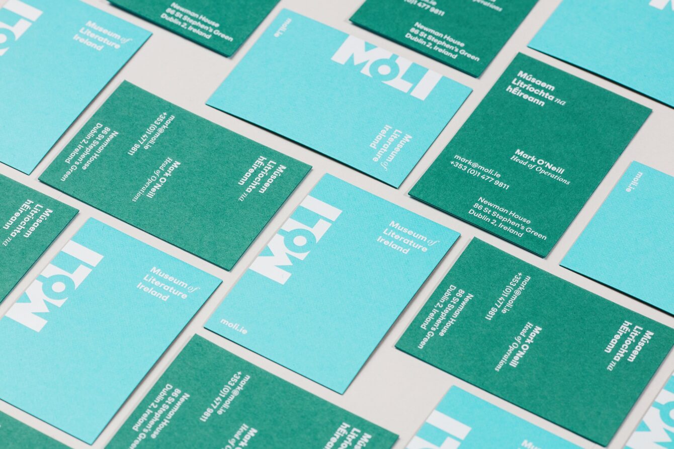Blue and green MoLI business cards knolled on a white table.